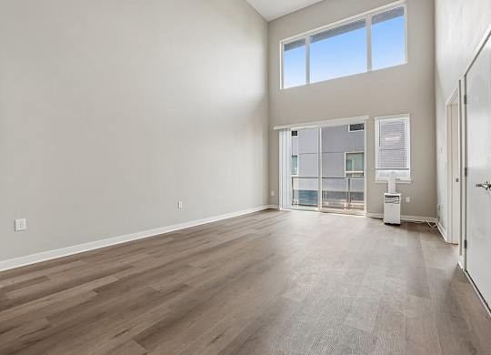 A large empty room with wooden flooring and a window.