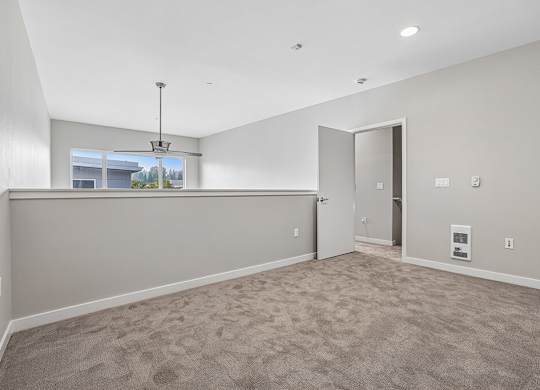 A room with a carpeted floor and a window showing a view of trees and a building outside.