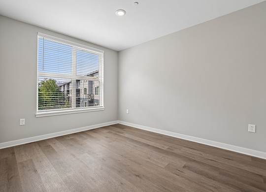 A room with a window and wooden flooring.