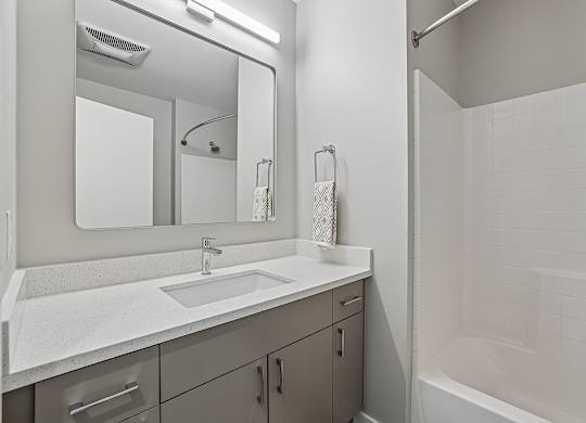 A white bathroom with a sink, mirror, and shower.