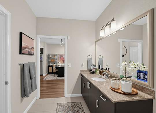A bathroom with a sink, mirror, and a framed picture on the wall.