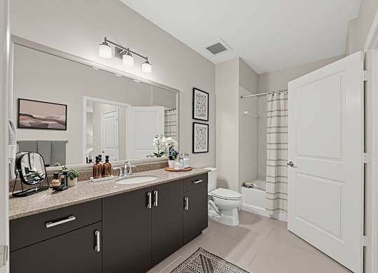 A bathroom with a sink, mirror, toilet, and shower.