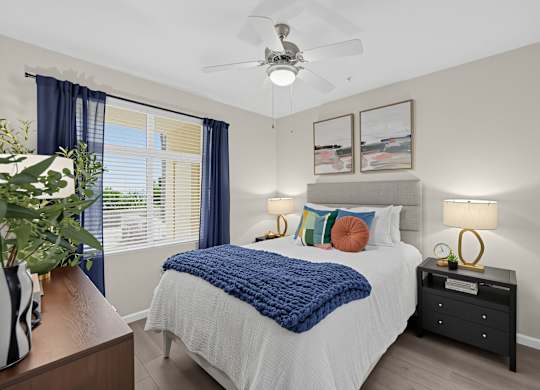 A bedroom with a bed, nightstand, and a ceiling fan.