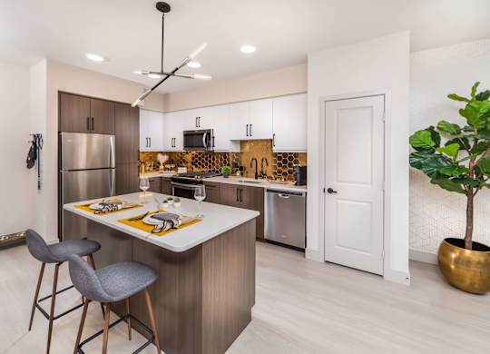 S kitchen with stainless steel appliances and a island with two stools at Avel Apartment Homes in Orange CA
