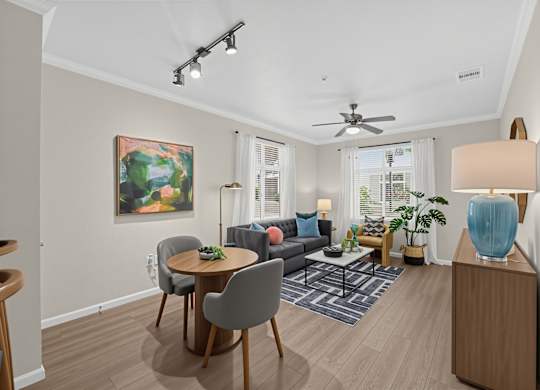 A living room with a grey couch, a round table, and a painting on the wall.