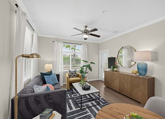 A living room with a grey sofa, a coffee table, a side table with a lamp, a mirror, and a wooden cabinet.