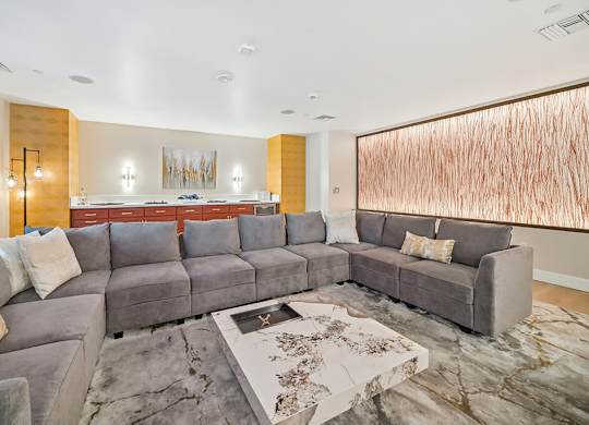 A modern living room with a grey sofa and a large abstract painting on the wall.