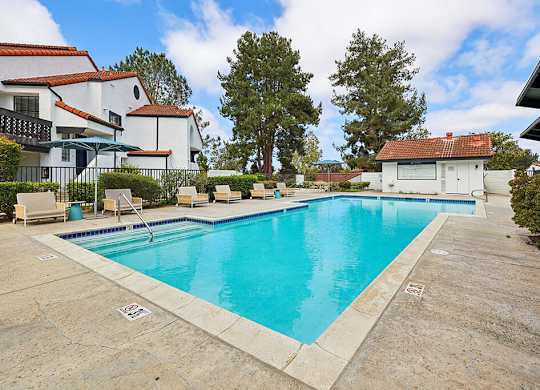 A swimming pool surrounded by a patio and a house.