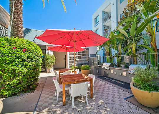 A patio with a table and chairs under a red umbrella.