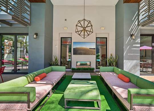 A modern living room with a green sofa and a hanging geometric light fixture.