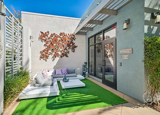A modern outdoor seating area with a white couch and a tree-shaped decoration.
