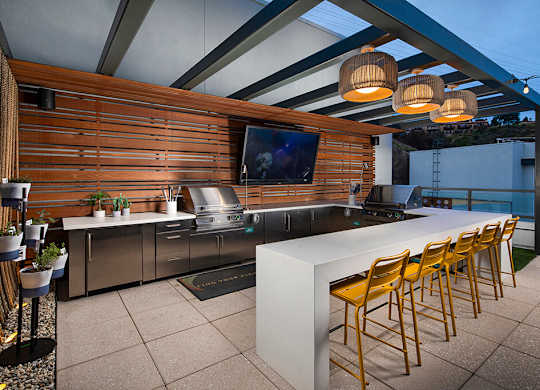A modern outdoor kitchen with a bar and chairs.
