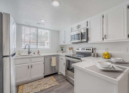 A modern kitchen with white cabinets and stainless steel appliances.