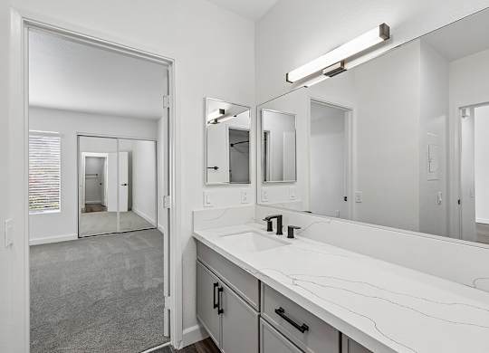 A bathroom with a sink, mirror, and a large mirror above the sink.