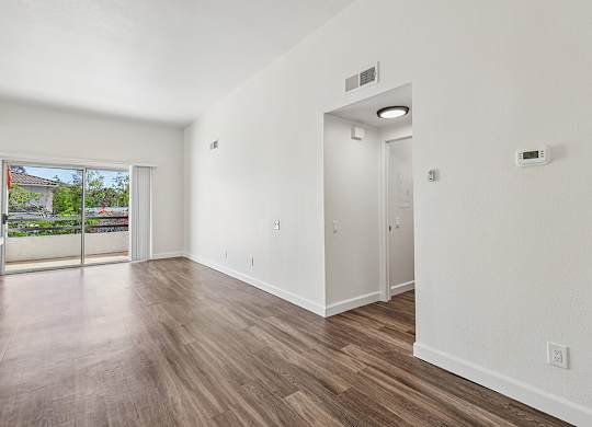 A room with a sliding glass door leading to a balcony.
