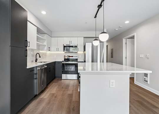 A modern kitchen with a white island and stainless steel appliances.