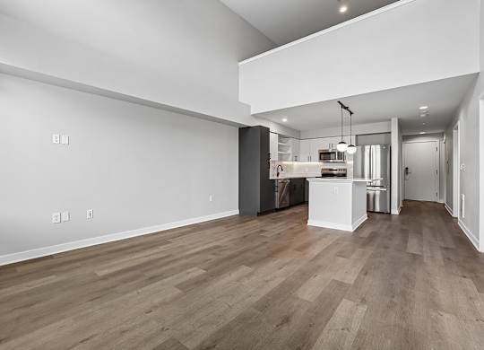 A kitchen area with a white wall and wooden flooring.