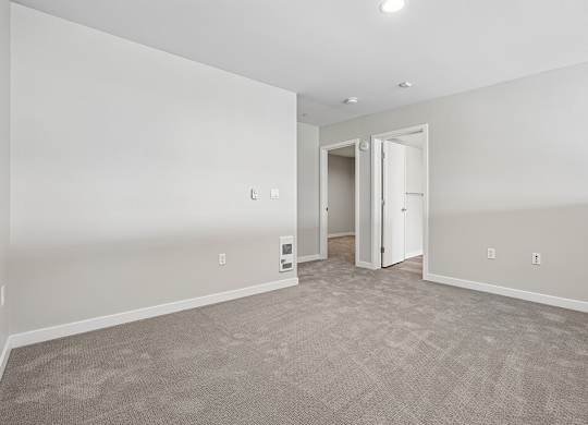 A room with a carpeted floor and a doorway leading to another room.