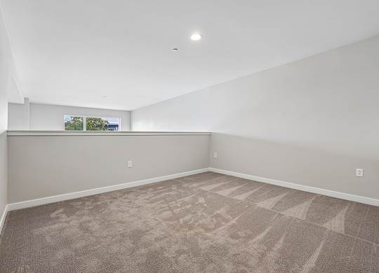 A room with a carpeted floor and a window showing a view of trees and a building.