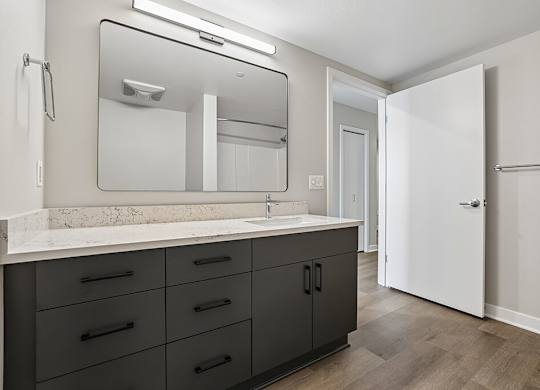 A bathroom with a marble countertop and a large mirror.