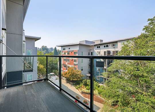 A balcony with a black railing overlooks a cityscape.