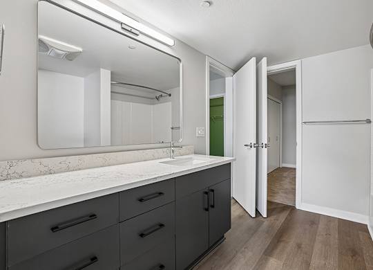A bathroom with a marble countertop and a large mirror.