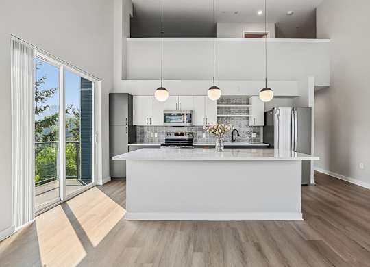 A modern kitchen with a large island and pendant lights.