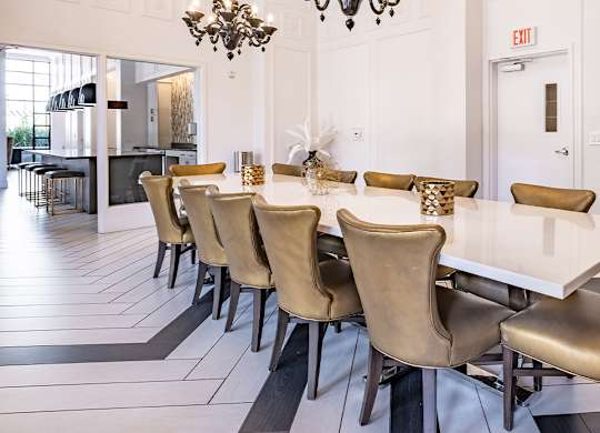 A long white table with chairs around it.