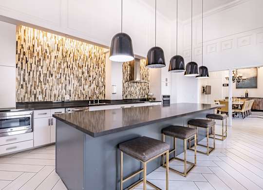 A modern kitchen with a dark countertop and bar stools.