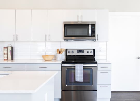 A modern kitchen with a black oven and white cabinets.