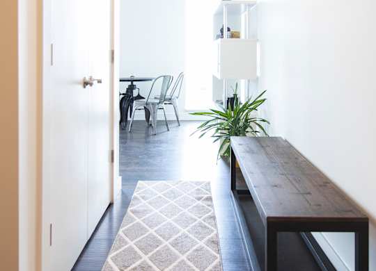 A long hallway with a bench and a rug.