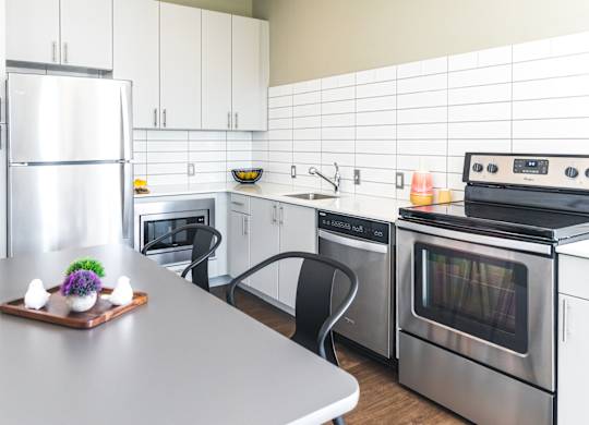 A modern kitchen with a refrigerator, oven, and microwave.