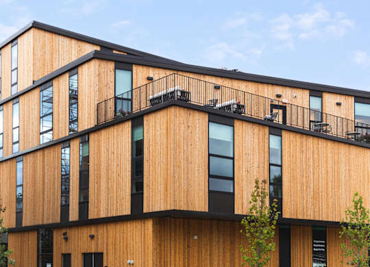 A modern building with a wooden exterior and balconies.
