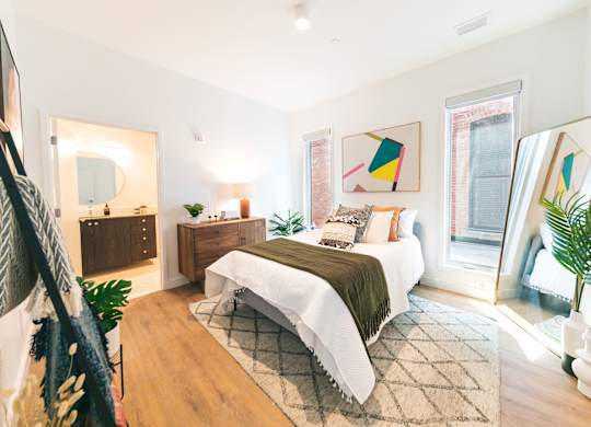 A bedroom with a bed, nightstand, and a mirror.