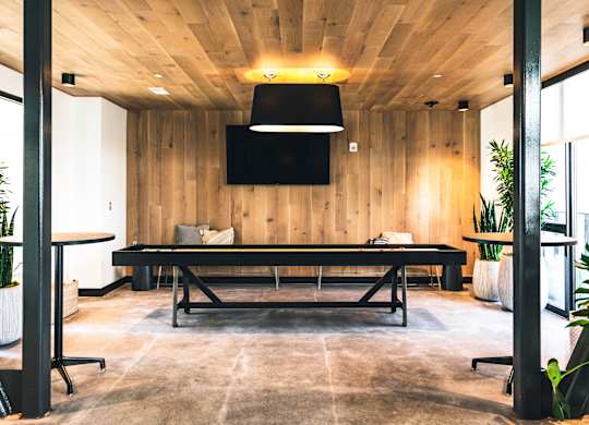 A conference room with a long table and a flat screen TV mounted on the wall.
