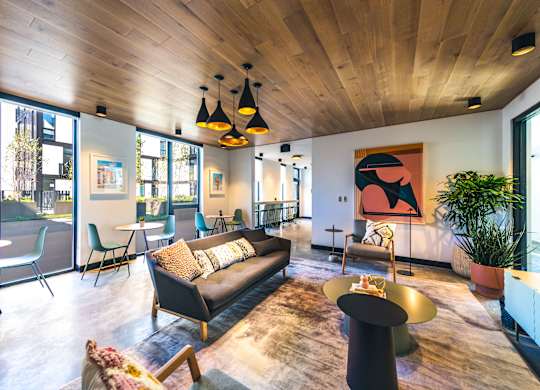 A living room with a black couch and a wooden ceiling.