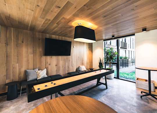 A room with a long black table and a television mounted on the wall.
