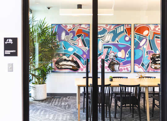 A room with a table and chairs and a painting on the wall.