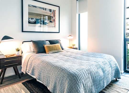A bedroom with a large bed and a framed picture on the wall.