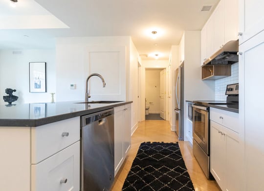 Fully equipped kitchen with stainless steel appliances includes refrigerator, stove, and dishwasher, at The Stott.