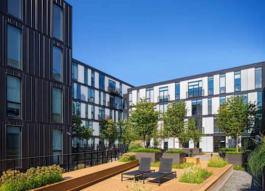 a rendering of a courtyard with tables and chairs in front of buildings
