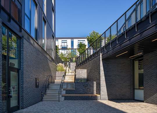 a set of stairs between two brick buildings with a blue sky in the background