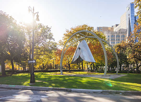 A large metal sculpture in the shape of a triangle is in the middle of Grand Circus Park