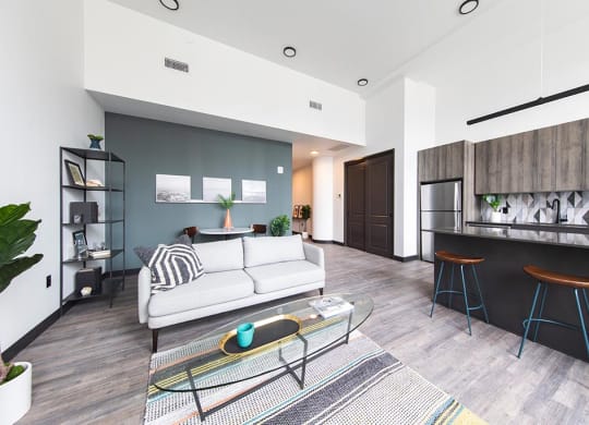 Modern living room and kitchen area with island and bar stool seating at The May.