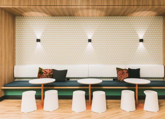 Community area with plush lounge benches, tables, and additional stool seating at The May.