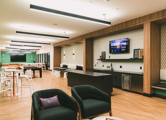 Community room with TVs, lounge area, and billiard table at The May.