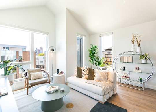 A living room with a white couch, a glass coffee table, and a large window.