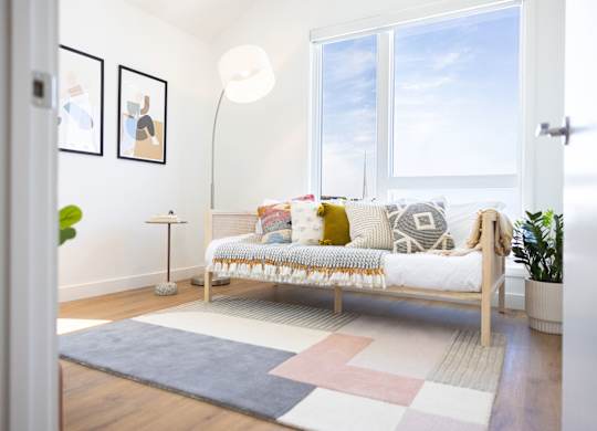 A cozy bedroom with a bed, pillows, and a lamp.