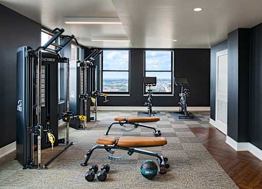 The Stott fitness center with a variety of equipment including a squat rack, bench, and weights.