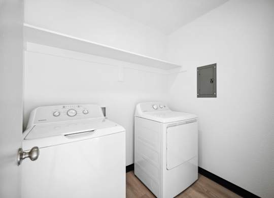 Two white washing machines in a laundry room.